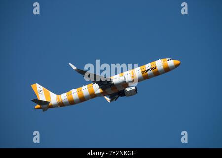 Un aeroplano commerciale Condor dipinto con strisce arancioni e bianche che vola in un cielo azzurro, Condor Aviation Company, decollo dell'Airbus A321 Foto Stock