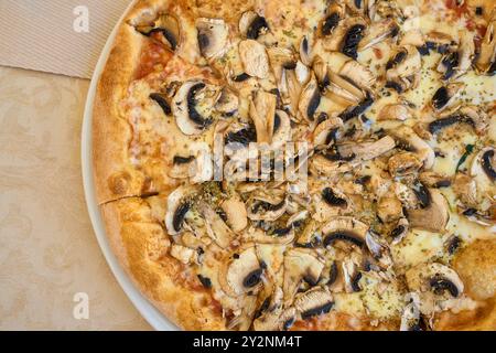 Porec, Istria, Croazia - 27 agosto 2024: Una pizza con formaggio e funghi freschi, cotta e servita su un piatto. Piatto tipico italiano con funghi e formaggio come ingredienti principali *** Eine Pizza mit Käse und frischen Champignons, gebacken und angerichtet auf einem Teller. Ein typisch italienisches Gericht mit Pilzen und Käse als Hauptzutaten Foto Stock