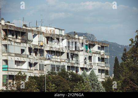 Un grande blocco di appartamenti in cemento grigio con balconi, aria condizionata, lavaggi e finestre nel centro di Podgorica, in Montenegro, in una giornata di sole Foto Stock