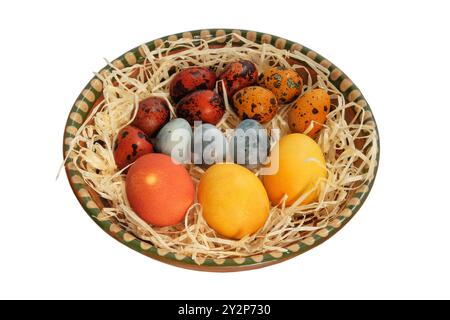 Uova di Pasqua in un piatto rustico. Isolare su sfondo bianco. Tradizioni pasquali. Varietà di uova dipinte. Arredi per la casa. Stile rustico. Foto Stock