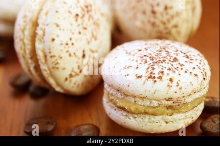 Primo piano di succulenti macaron tiramisù con chicchi di caffè sparsi Foto Stock