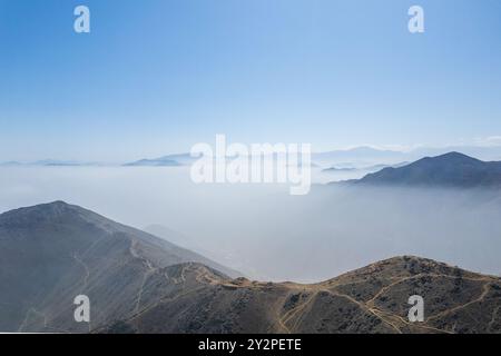 Il cielo è limpido e blu con qualche nuvola. Le montagne sono coperte di nebbia Foto Stock