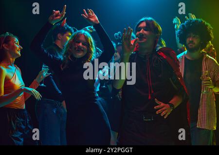 Giovani, uomini e donne vestiti con costumi a tema, con un trucco inquietante, partecipare alla festa di Halloween al nightclub, ballare, ridere Foto Stock