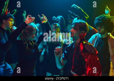 Giovani, uomini e donne vestiti con costumi a tema, con un trucco inquietante, partecipare alla festa di Halloween al nightclub, ballare, ridere Foto Stock
