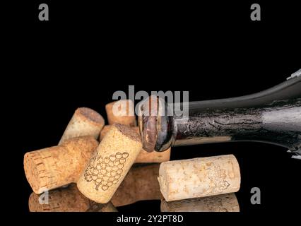 Diversi sugheri di vino con una bottiglia di vino vecchio, macro, isolato su sfondo nero. Foto Stock