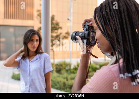 Una giovane donna con i capelli intrecciati cattura le foto di una studentessa, documentando in modo creativo la vita del campus mentre si preparano alle sfide universitarie e. Foto Stock