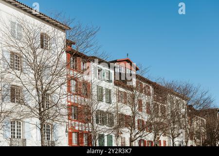 Una fila di tradizionali case basche a Bayonne, con le loro tipiche facciate bianche e le persiane rosse, sotto un cielo azzurro. Foto Stock