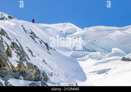 Vista posteriore di un alpinista anonimo che sale su un pendio innevato nelle Alpi svizzere, vicino a Zermatt. La persona, irriconoscibile per essere stata fotografata da b Foto Stock