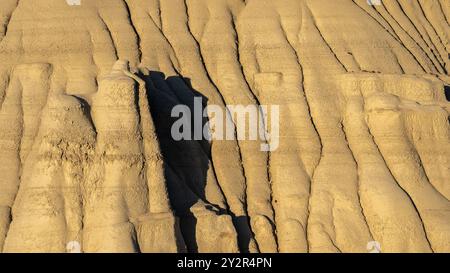 Incredibile ripresa aerea di formazioni rocciose erose illuminate dal sole che mostrano profonde scanalature e linee testurizzate nella natura selvaggia di Ah-Shi-SLE-Pah, New Mexico Foto Stock