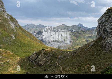 Dei lussureggianti e aspri paesaggi dei Pirenei francesi, catturando l'ampia distesa di verdi valli rocciose e vette lontane sotto un cielo nuvoloso. Foto Stock