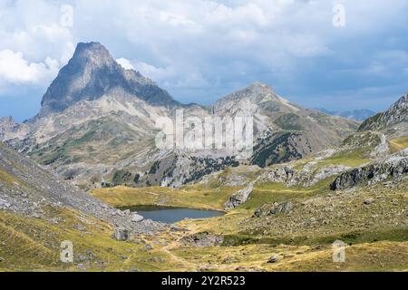 Lo scatto aereo cattura un'imponente vetta di montagna accanto a un tranquillo lago nei Pirenei francesi, mostrando l'aspra bellezza e il suggestivo paesaggio di Th Foto Stock