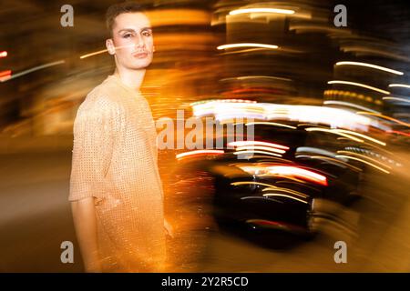 Una persona non binaria posa tra calde e dinamiche strisce di luce, creando un effetto astratto e sfocato dal movimento. Foto Stock