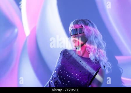 Una donna all'avanguardia che indossa una visiera futuristica è audace, incapsulando l'intersezione tra stile e tecnologia in un metaver surreale e vibrante Foto Stock