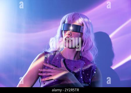 Una donna futuristica immersa in un'esperienza metaversa, che indossa una visiera e immersa in una vibrante luce viola, evocando temi di tecnologia e re virtuale Foto Stock