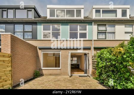 Una moderna casa cittadina a due piani con una porta frontale aperta, un ingresso invitante e una facciata in mattoni sotto un cielo nuvoloso. Foto Stock