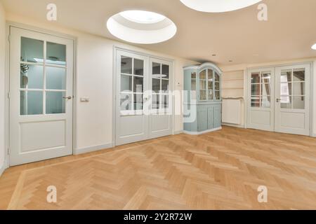 Gli interni eleganti di una spaziosa camera presentano pavimento in parquet a spina di pesce, grandi porte francesi e lampade contemporanee. Foto Stock