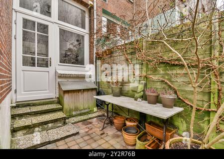 Un invitante piccolo giardino urbano che presenta una panchina in vaso di legno, vasi di fiori vuoti e piante da arrampicata su un traliccio. Foto Stock