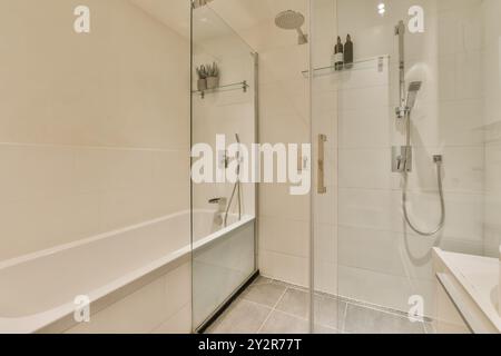 Un bagno moderno ed elegante con cabina doccia in vetro accanto a una vasca bianca, illuminata da luci soffuse. Foto Stock