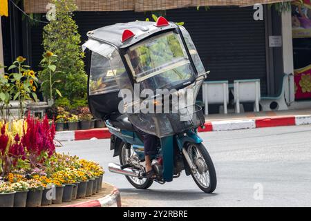 BETONG, THAILANDIA, Mar 02 2024, Una donna anziana guida una moto con un tetto Foto Stock