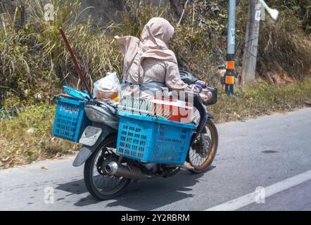 BETONG, THAILANDIA, Mar 02 2024, una donna sta trasportando un carico su una moto Foto Stock