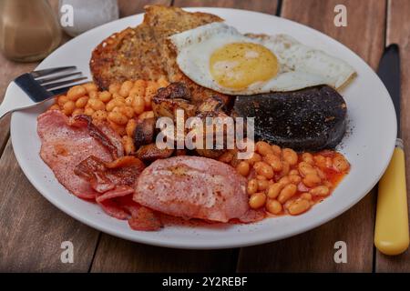 Colazione all'americana con budino nero, pancetta, funghi, fagioli, pane fritto e uova fritte. Foto Stock