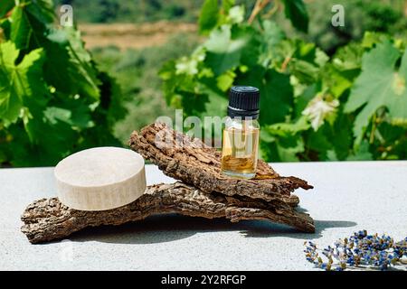 Bottiglia con olio di lavanda naturale essenziale e sapone di lavanda fatto in casa su corteccia di legno come podio per la presentazione del prodotto. Aromaterapia, alternati Foto Stock