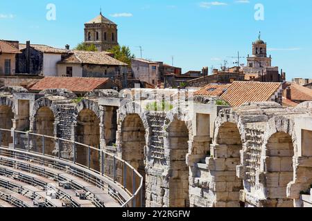 L'interno dell'anfiteatro romano di Arles, Provenza, Francia, guarda verso la torre della chiesa di San Trofeo sui tetti Foto Stock