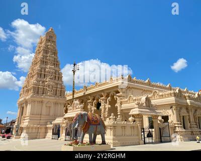 Un tempio indù splendidamente dettagliato con un cielo azzurro e una statua di un elefante di fronte Foto Stock
