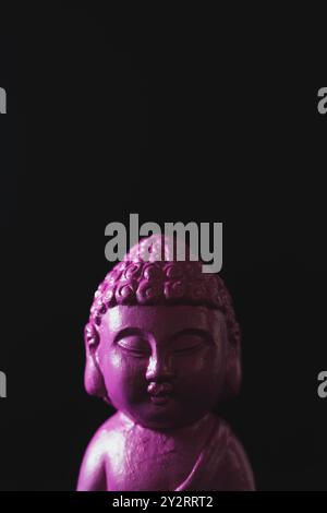 Una figura di Buddha rosa su sfondo nero. Foto Stock