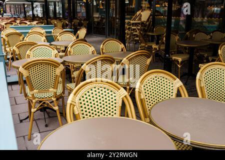 Sedie di vimini vuote e tavoli al caffè europeo all'aperto in una giornata nuvolosa Foto Stock