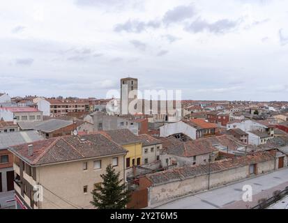 Una vista panoramica di una città europea con una torre storica e tetti piastrellati sotto un cielo nuvoloso. Cuellare. Segovia Foto Stock