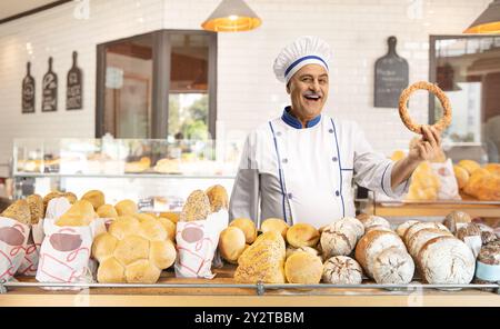 fornaio maschio maturo che tiene un simit all'interno di una panetteria Foto Stock