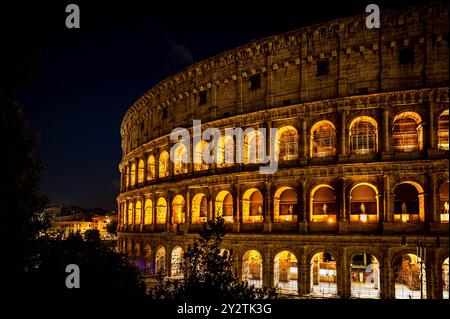 Vista notturna del Colosseo di Roma, in Italia, splendidamente illuminato con luci dorate contro un cielo scuro. Foto Stock