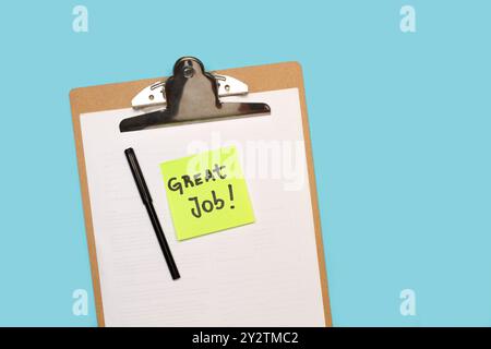 Ottimo lavoro scritto a mano su carta adesiva su un tavolo degli appunti con fogli di carta bianca su sfondo azzurro Foto Stock