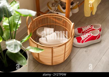 Cestino con pantofole per gli ospiti e scarpe da ginnastica all'ingresso di casa Foto Stock