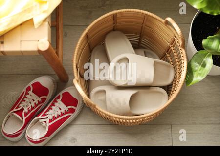 Cestino con pantofole per gli ospiti e scarpe da ginnastica nell'ingresso di casa, vista sopra Foto Stock