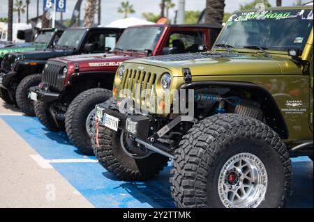 Jeep Wrangler JK gialla di terza generazione, modificata per un fuoristrada estremo in primo piano, ma accanto ad essa sono parcheggiate altre Jeep Foto Stock