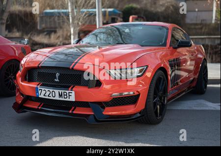 Vista frontale di una spettacolare auto sportiva americana Ford Mustang di sesta generazione, arancione-rosso con una striscia nera Foto Stock