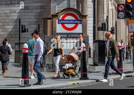 Una coppia con un passeggino che passa davanti all'ingresso di Princes Street alla stazione della metropolitana Bank presso Bank Junction nella City di Londra, Londra, Regno Unito Foto Stock