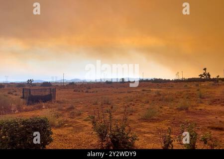 Hesperia, CALIFORNIA, USA - 10 settembre 2024: Il fumo proveniente dagli incendi delle brughiere nelle montagne della California meridionale crea un cielo arancione nel deserto del Mojave. Foto Stock