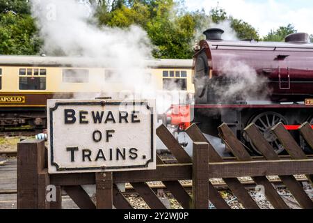 Attenzione al cartello di avvertimento dei treni all'incrocio pedonale della stazione ferroviaria di Wirksworth. Foto Stock