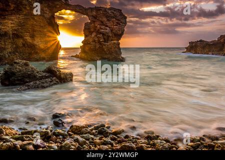 Una spiaggia di ciottoli e insenatura con un arco a Cabo Rojo al tramonto, situata nel punto sud-occidentale di Puerto Rico Foto Stock