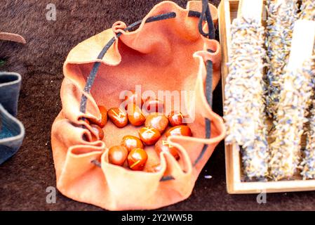 Primo piano di un sacchetto di pelle contenente pietre rune accanto a un vassoio di erbe essiccate. Foto Stock