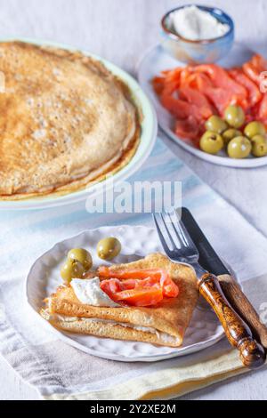 Pancake con gravlax, formaggio fresco e olive. Un piatto tradizionale per Maslenitsa o Carnevale. Foto Stock