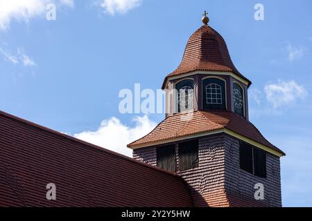 Una vista ravvicinata di un campanile della chiesa con una caratteristica cupola e facce a orologio, adagiata su un cielo blu luminoso con soffici nuvole. Le caratteristiche della struttura Foto Stock