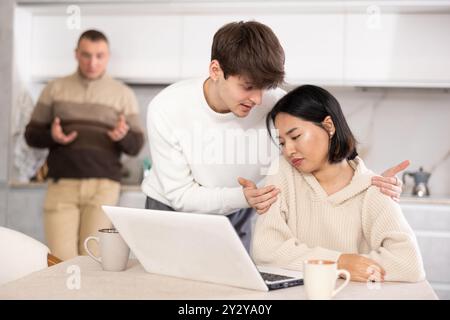 Un ragazzo convince una giovane ragazza a smettere di giocare ai videogame. Padre turbato in sottofondo Foto Stock