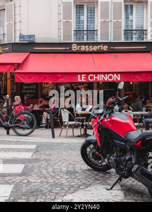 Parigi - 4 settembre 2024 - foto di strada di French Street a Montmartre con caffè e brasserie e Red Motorbike Foto Stock