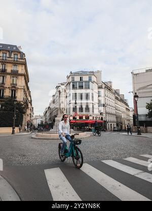 Parigi - 4 settembre 2024 - pittoresca strada francese con caffè e ciclista al 9° arrondissement Foto Stock