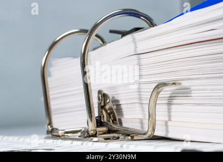 Primo piano di un file metallico di cartelle cartacee mantenendo automatico l'ufficio di oggetti concettuali di varie aziende Foto Stock