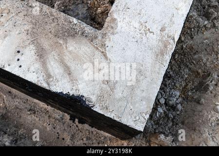 L'angolo di una base a nastro in cemento armato è ricoperto da una composizione bituminosa nera protettiva, vista dall'alto Foto Stock